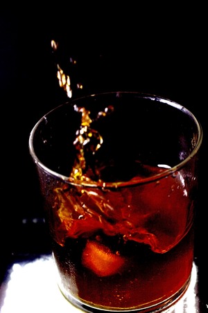 Glass of whiskey with falling ice cubesの写真素材
