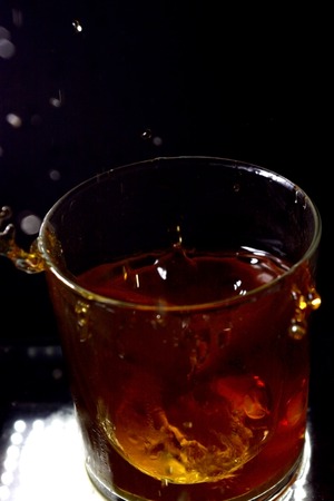 Glass of whiskey with falling ice cubesの写真素材