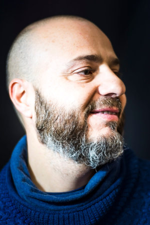 Handsome, bald man with beard on black background