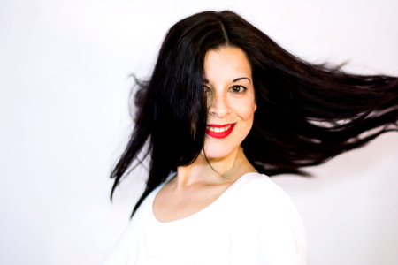 Portrait of Beautiful Young Woman Shaking Her Hair Over White Backgroundの写真素材