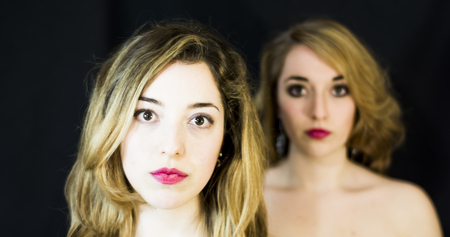 Two beautiful women Portrait Isolated over Black Backgroundの写真素材