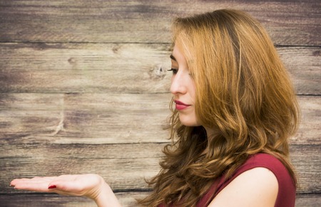 Beauty Woman with her open hand Portrait Isolated over Wooden Backgroundの写真素材