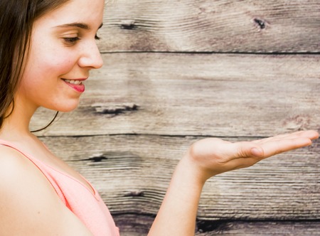 Portrait of a beautiful woman with her open hand on wooden backgroundの写真素材