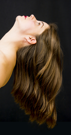 Portrait of a beautiful woman with hair in the wind on black backgroundの写真素材