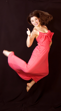 Portrait of a beautiful woman jumping on black backgroundの写真素材