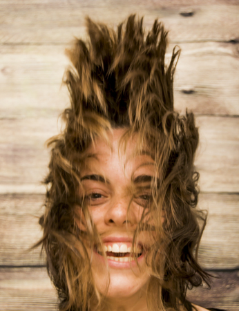 Portrait of Beautiful Young Woman Shaking Her Hair Over Wooden Backgroundの写真素材