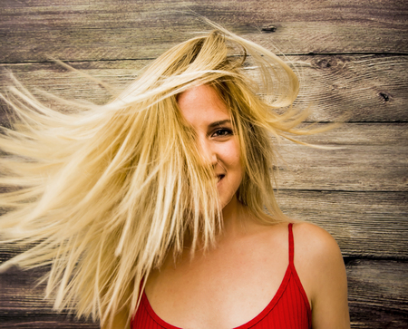Portrait of Beautiful Young Woman Shaking Her Hair Over Wooden Backgroundの写真素材