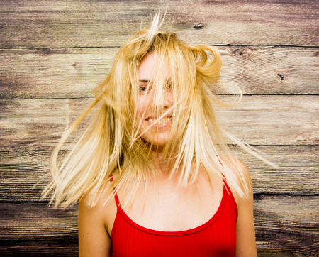 Portrait of Beautiful Young Woman Shaking Her Hair Over Wooden Backgroundの写真素材