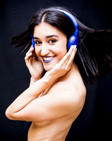 Beautiful woman with headphones on black backgroundの写真素材