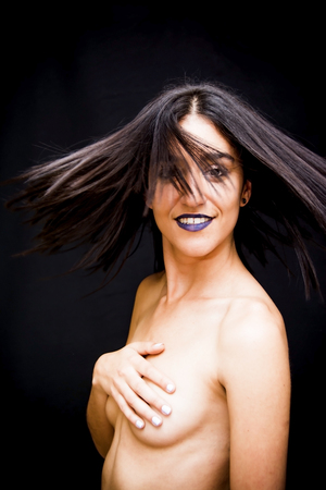 Beautiful topless woman covering her breasts on black backgroundの写真素材