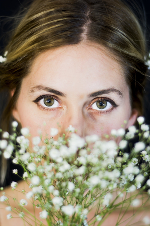 Portrait of a beautiful Woman with white flowers as a bride on her wedding day on black backgroundの写真素材