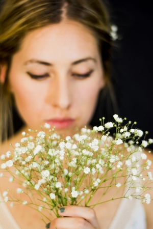 Portrait of a beautiful Woman with white flowers as a bride on her wedding day on black backgroundの写真素材