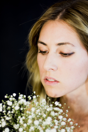 Portrait of a beautiful Woman with white flowers as a bride on her wedding day on black backgroundの写真素材