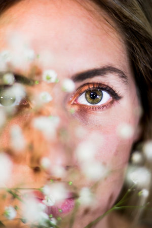 Portrait of a beautiful Woman with white flowers as a bride on her wedding day on black backgroundの写真素材