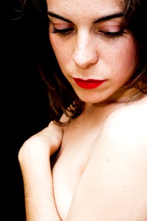 Portrait of a beautiful woman  covering her breasts with her arms on black backgroundの写真素材