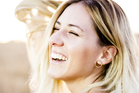 Beautiful blond woman in a red dress, on a wheat field at sunsetの写真素材