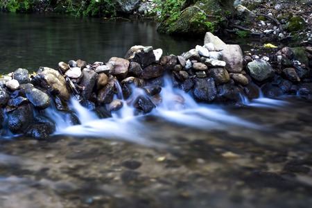 Landscape of a river with water running silky, rocks and treesの写真素材