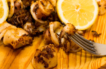 Fried squids and shipirons  with lemon on a wooden plate