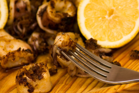 Fried squids and shipirons  with lemon on a wooden plateの写真素材