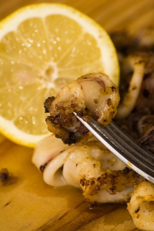 Fried squids and shipirons  with lemon on a wooden plateの写真素材