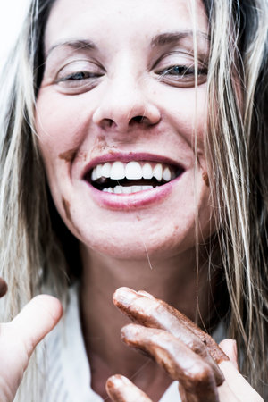 Portrait of Beautiful woman with fingers stained with chocolateの写真素材