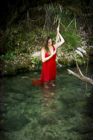 Beautiful woman on the bank of a mountain river with an evening dressの写真素材