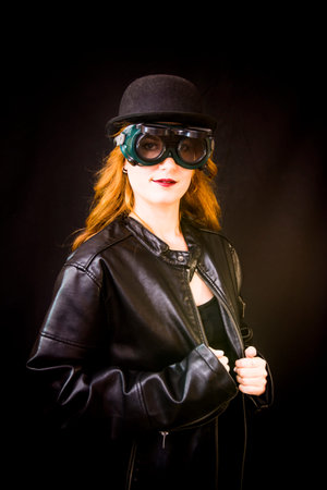 Portrait of a beautiful woman with special glasses and hat on black backgroundの写真素材