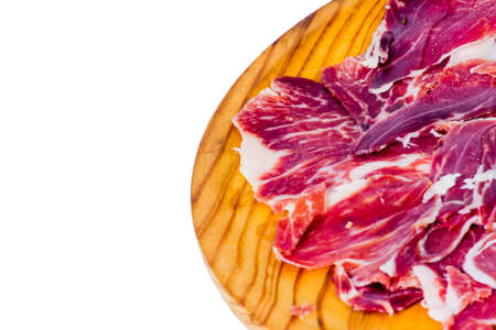 Typical spanish tasty portions of ham on wooden tray on white backgroundの写真素材