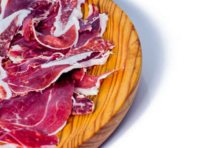 Typical spanish tasty portions of ham on wooden tray on white backgroundの写真素材