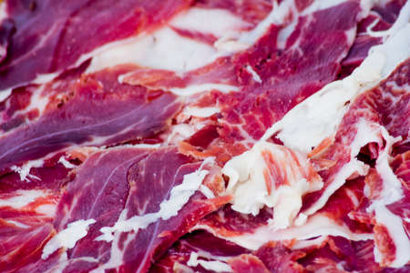 Typical spanish tasty portions of ham on wooden tray on white backgroundの写真素材