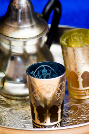 Group of teapot and glasses of oriental tea on a tray on blue background with glitterの写真素材