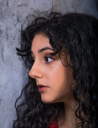 Portrait of beautiful woman in red dress on background of a concrete wallの写真素材