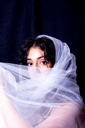 Portrait of a beautiful woman with white veil on black background