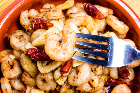 Tasty Prawns with garlic and cayenne in a ceramic bowl on a wooden trayの写真素材