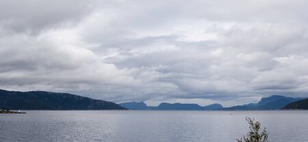 View of the landscape of a wide fjord in Norway on an autumn day with some rain clouds gatheringの写真素材
