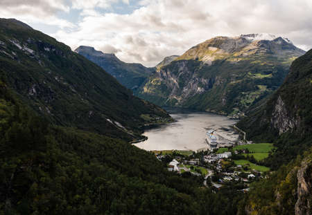 Majestic and big Geiranger fjord with sun peaking from behind the dark clouds on a late summer dayの写真素材