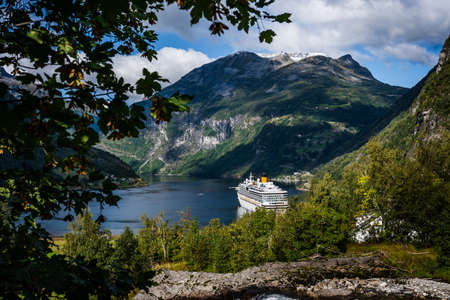 Majestic and big Geiranger fjord with sun peaking from behind the dark clouds on a late summer dayの写真素材