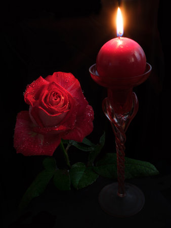 Red rose and candle on black background. Valentines day background.の写真素材