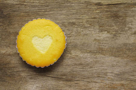 Heart shape on cupcake surface on wooden backgroundの写真素材