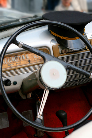 Dashboard of old car with steering wheel and cap of driver, souvenir of the communism eraの写真素材