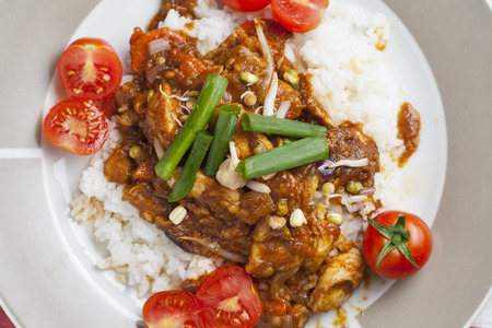 Szechuan chicken with white rice on a plate decorated with chive and cocktail tomatoの写真素材