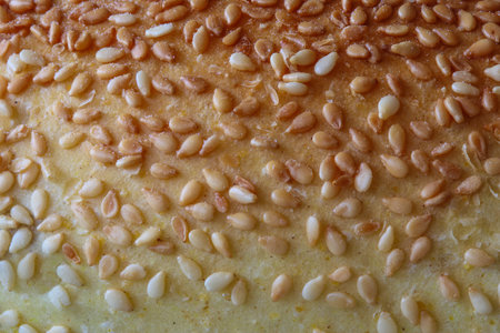 Macro close up of fresh corn bread roll surface with sesame seeds as background