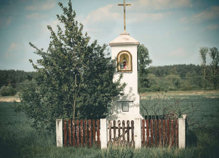 Old wayside shrine in polish countryside stand amid fields of ryeの写真素材
