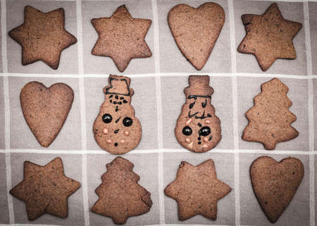 Hand decorated by children christmas gingerbread snowman cookie figurine amids other undecorated cookiesの写真素材