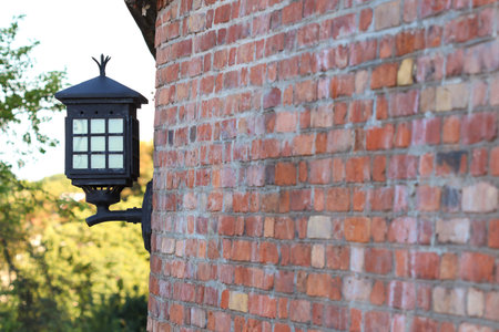 Old steel electric lantern attached to red brick wallの写真素材