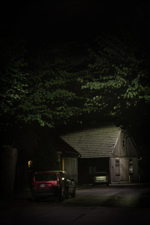 Old wooden house illuminated at the end of dark silent and empty street