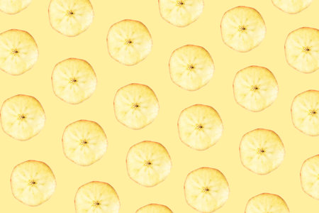 Pattern made of slices of Jonagold apples on yellow background