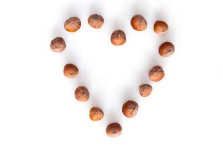 Heart shape made of whole hazelnuts on white backgroundの写真素材