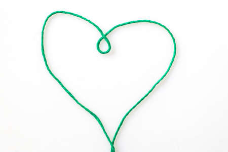 Heart shape made of green cord on white backgroundの写真素材