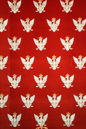 Silver eagles in crown embroidered on the red material as background of throne chair